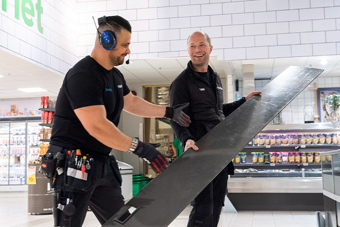 Bilden visar två kyltekniker som gör en installation av en kylanläggning i butiksmiljö