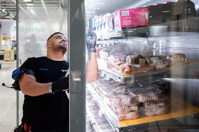 A refrigeration technician doing an installation and service in a refrigerated display cabinet